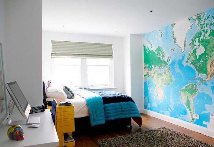 en fotoband med den geografiska världskartan, blå duvet och det vita skrivbordet - trevligt rum