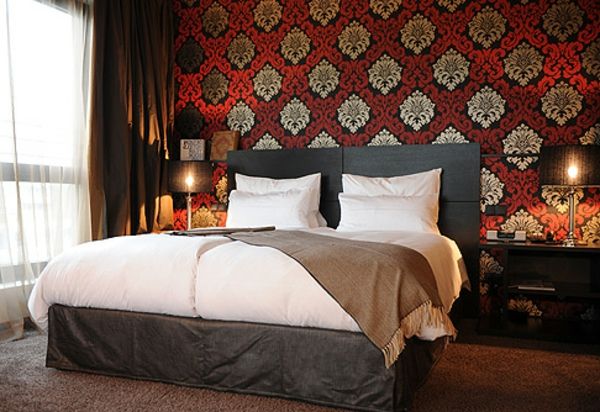 beli pokrivni pokrivač in ozadje z rdečimi in zlati barvnimi šabloni v spalnici