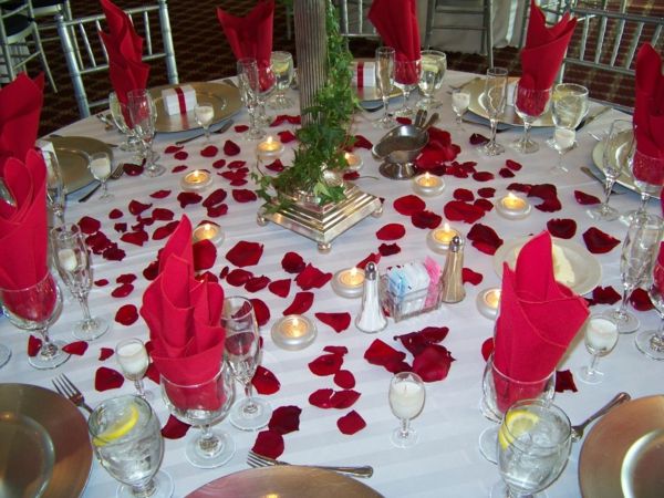 röda servetter i glasagtigt vitt tak och röda rosenblad - idéer för festdekoration