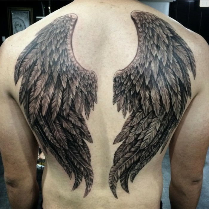 človeka in njegovega angelskega tetovaža z dvema črnima angelskima kriloma z dolgimi črnimi peruti