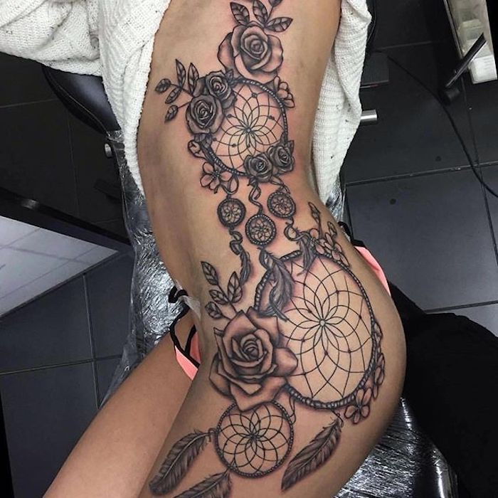 Her er en tatovering med en stor svart drømfanger med roser. og fjær