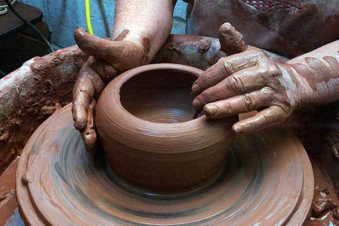 un uomo con mani grandi, che lavora al giradischi e produce stoviglie di terracotta