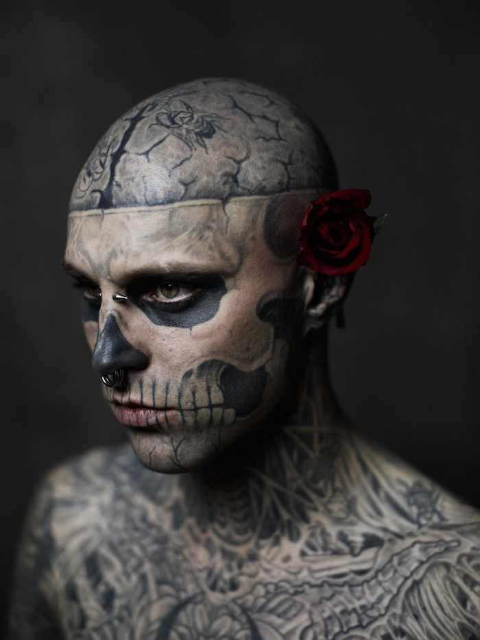 En mann med en rød rose og en stor tatovering med en skalleskalle og hvite tenner
