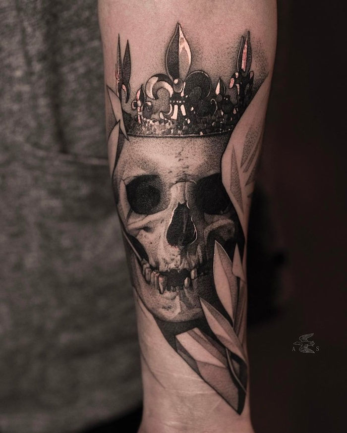 En hånd som holder en stor tatovering med en hvit hodeskalle med svarte øyne og en krone