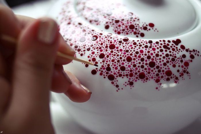 una piccola teiera di colore bianco con piccoli e grandi punti rossi