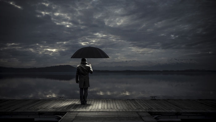 Siyah bir şemsiye ile yalnız bir adamla başka bir üzücü resim. deniz ve gökyüzü gri ve siyah bulutlar - ağlamak için üzgün resimler