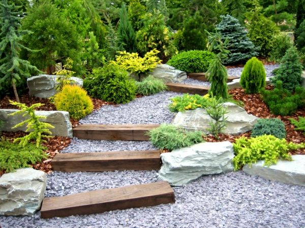 designer trädgård med många gröna växter och hemlagad trappa