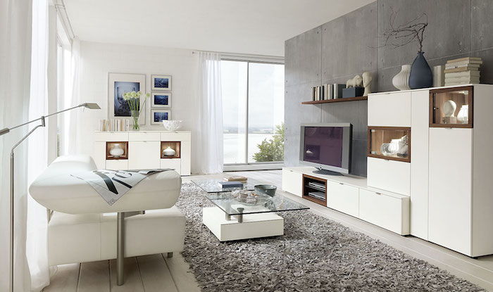 ściana mieszkalna biały duży biały szafka, na której znajduje się telewizor puszysta sofa szklana stół
