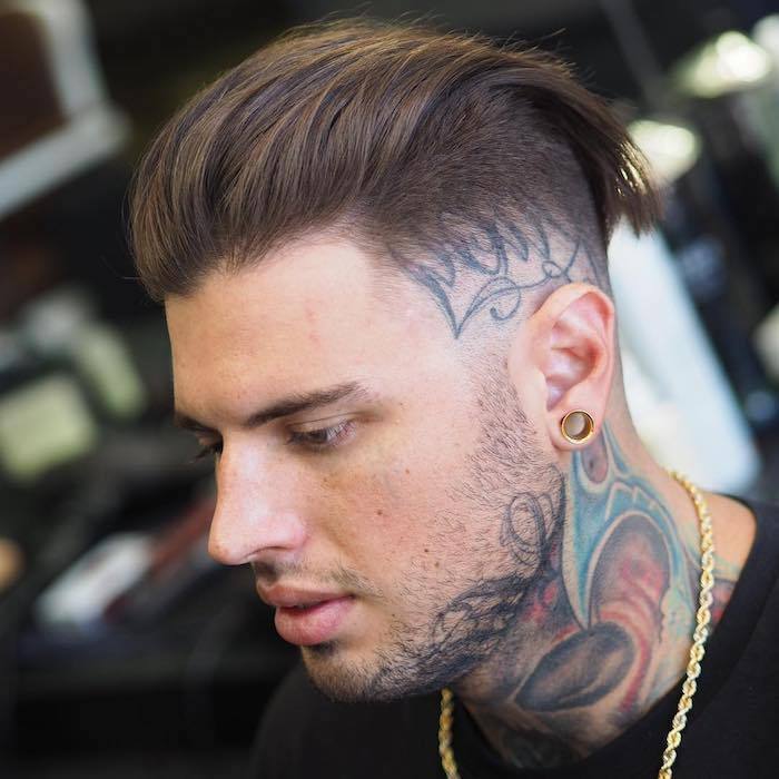 Sidecut mäns tatuering på huvudet under frisyren som matchar tatueringstilen