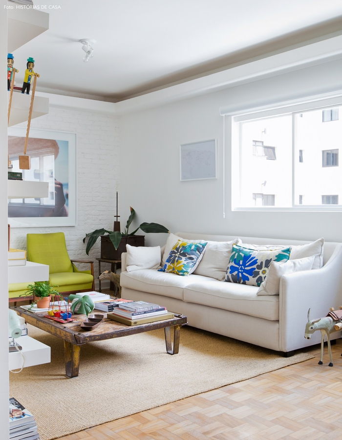 Stilingas gyvenamasis kambarys, balta sofa, spalvingos dekoratyvinės pagalvės, nedidelis staliukas, kambariniai augalai