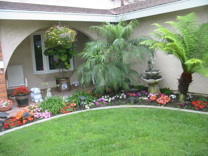 Palme, fontane in viseče cvetlične lončke in vrtne figure - lepo dvorišče