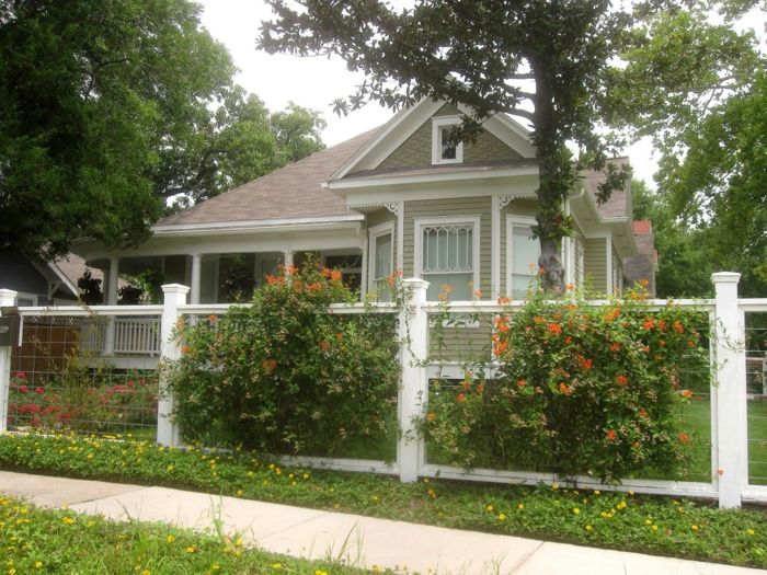 oranžne rože, bela ograja, visoka drevesa - lepi frontni vrtovi, ljubka hiša