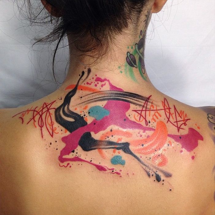 Un tatuaj colorat cu acuarelă, cu modele abstracte, cum ar fi pete în culori roz și portocaliu