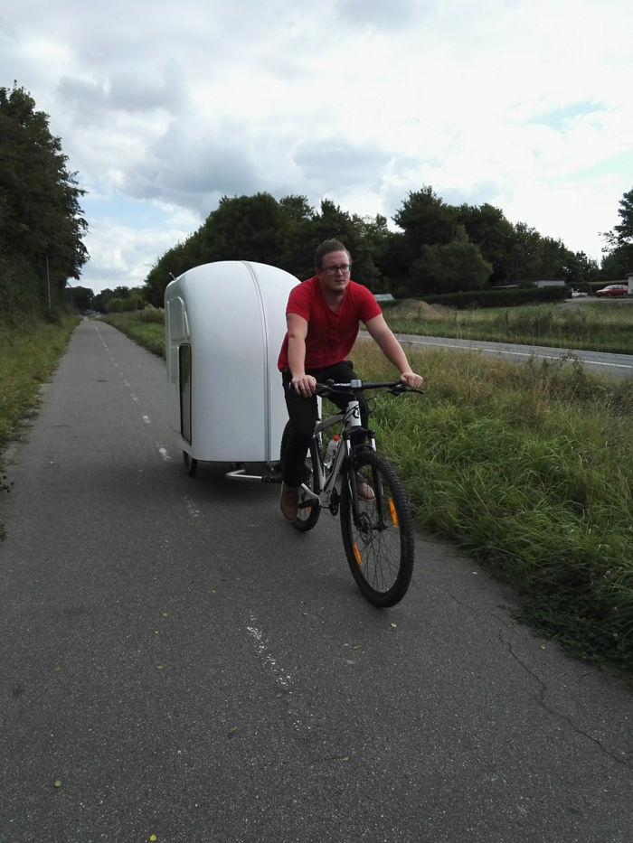 aqui é um ciclista no caminho com uma caravana de bicicleta branca