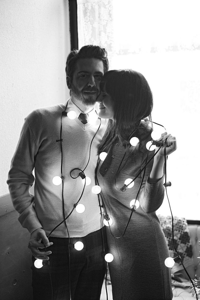 Julfoton - två älskare tar bilder i vardagsrummet med en feljus