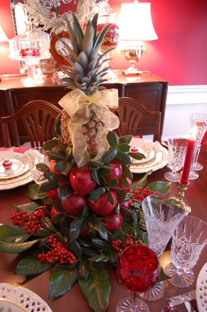 Kalėdų išdėstymas vaisių - obuolių ir ananasų, apsuptų žalių šakų