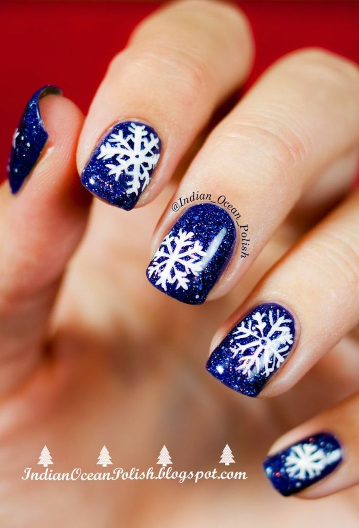 vita snöflingor på en mörkblå bakgrund, idé för glitterspikar för omformning, vinklig nagelform