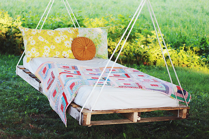 hangend bed gemaakt van oude europallets met kussens - idee op het gebied van palletmeubilair voor de tuin