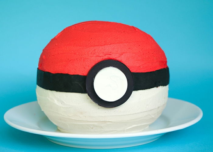 čia yra balta plokštė ir raudona pokemonio pyragas - šis pyragas atrodo kaip raudonas pokeballas