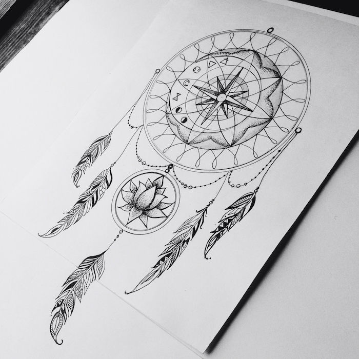 En annen av våre ideer til en tatovering med en svart drømfanger med lange svarte fjær og en blomst og et kompass