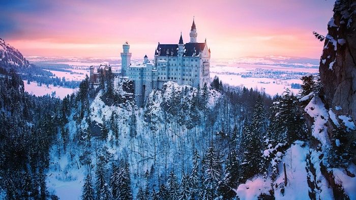 veľký biely hrad v západu slnka - les so snehom a stromami - obloha s ružovými mraky
