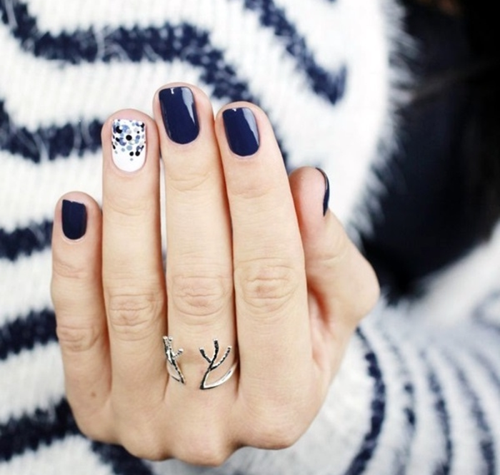 Vinterig nagel design i mörkblå och vit med prickar, oval nagelform, snygg tröja i bakgrunden
