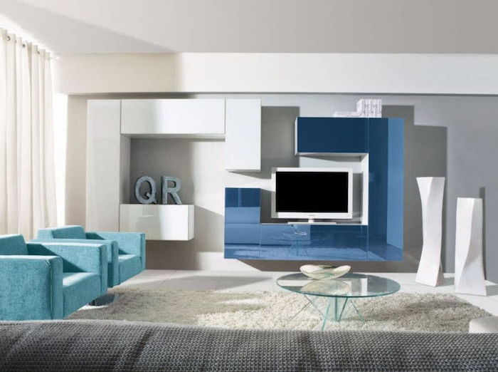 skrinka nástenná televízna stena v modrom a bielom sklenenom stole v strede miestnosti dve modré kreslá