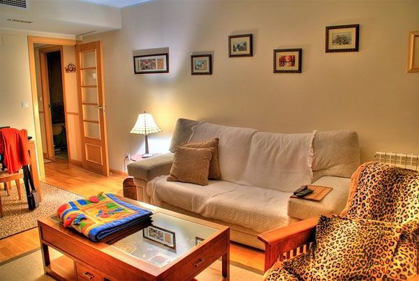 Obývacia izba s dreveným hniezdnym stolom, leopardovým kreslom, obrazmi na stene