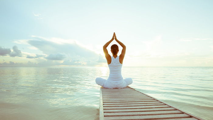 Float yoga bij zonsondergang aan zee, groen-wit zeewater, strek armen naar de hemel