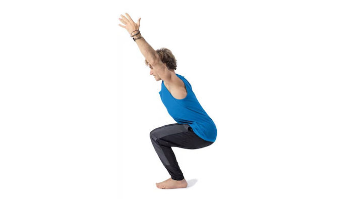 Yoga voor beginners: oefening Utkatasana, knielende man met uitgestrekte armen, drie zwarte armbanden, man met licht haar in sportuitrusting