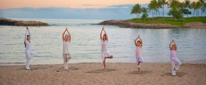 drie vrouwen en twee kinderen die yoga doen op het strand, twee kleine eilanden met palmbomen, zonsondergang