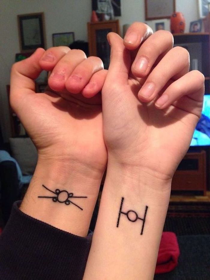 idee pentru tatuaje pentru cuplu pe încheietura mâinii - două mâini cu tatuaje negre mici, cu nave spațiale care zboară stele