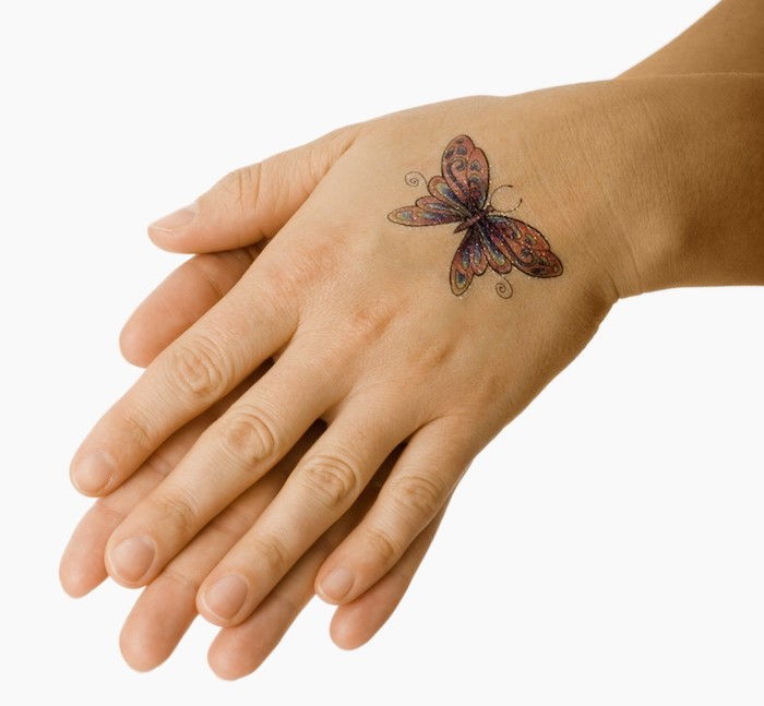 tu sú dve ruky a farebné, malé lietajúce motýľ s farebnými krídlami - nápad na úžasné motýľ tetovanie