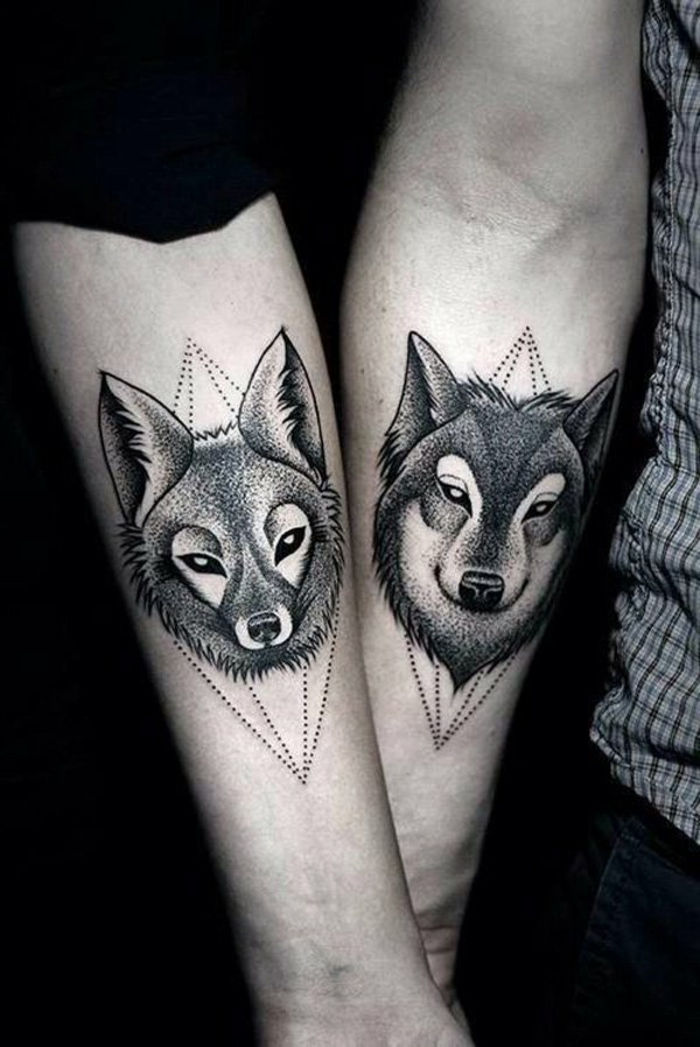 un tânăr iubitor, două mâini și două tatuaje negre mari - o vulpe și un tatuaj lup lupus