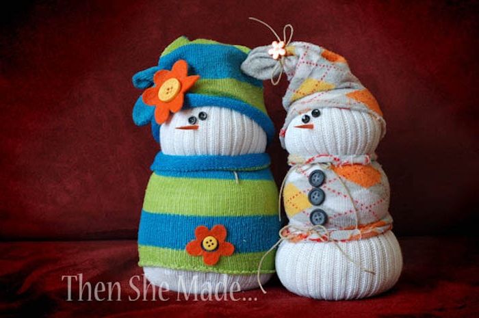 dve beli snežaki iz belih nogavic - z lupino, klobuki, črnimi očmi in sivimi gumbi ter pomarančami in rdečimi cvetovi